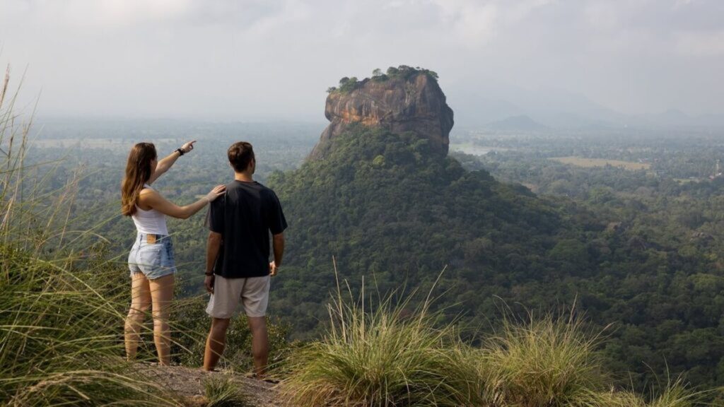 Travellers on Pidurangala Rock looking across the jungle to Sigiriya Rock Fortress on a Sigiriya day trip in Sri Lanka